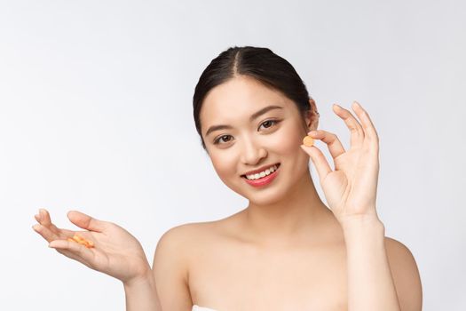 Young attractive asian woman who takes a capsule or pill. Isolated over white background