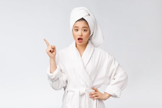 Beauty portrait of young woman showing and pointing finger to empty copy space, asian beauty in bathrobe