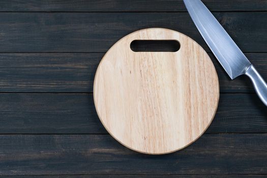 Close up kitchen knife and wooden round empty cutting board on a wooden table