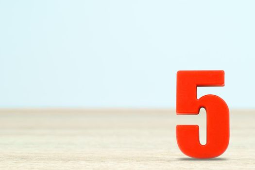 Shot of a number five made of red plastic on table with copy space