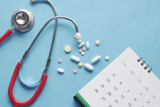 top view of pills and stethoscope on calendar