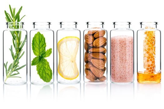 The glass bottle of homemade skin care and body scrubs with natural ingredients isolated on white background.