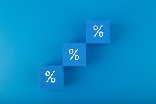 Toy blocks as a ladder with percentage sign on dark blue background. Modern concept of inflation, percent, mortgage or interest rate growth