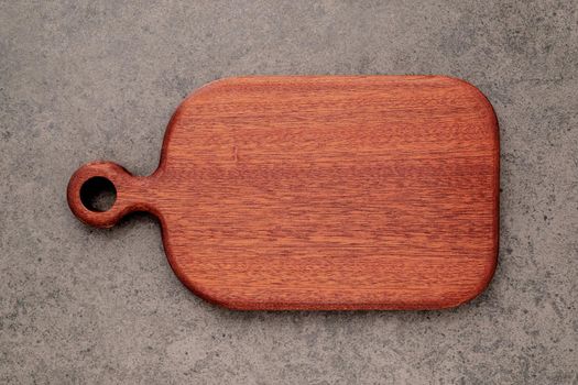 Empty vintage wooden cutting board set up on dark concrete background with copy space.