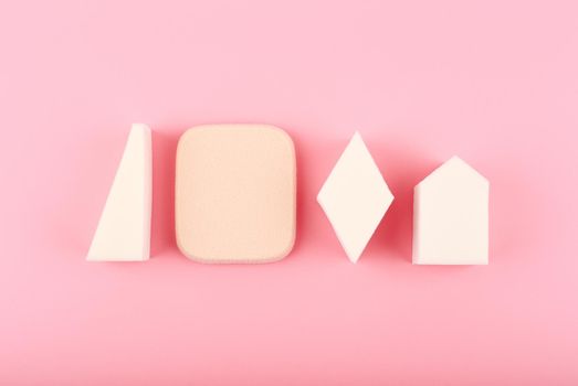 Different shapes make up sponges in a row on bright pink background. Concept of make up sponges, beauty blenders and art of visage 