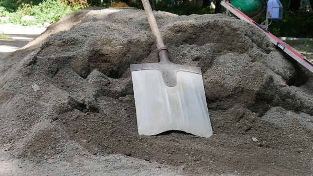 The shovel for dripping is lying on the pile of dry concrete or cement, construction and development concept.
