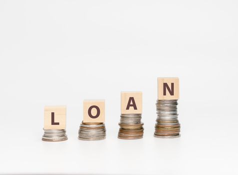 Stack coins and wooden cube with word LOAN