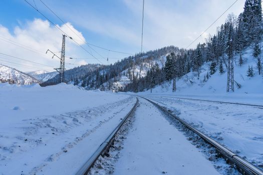 Railway in the snow passing in the shade between the mountains in winter