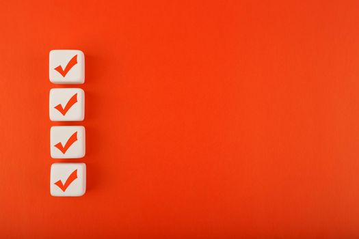 Four red checkmarks on white cubes in a row against blue background with copy space. Concept of questionary, checklist, to do list, planning, business or verification. Modern elegant flat lay