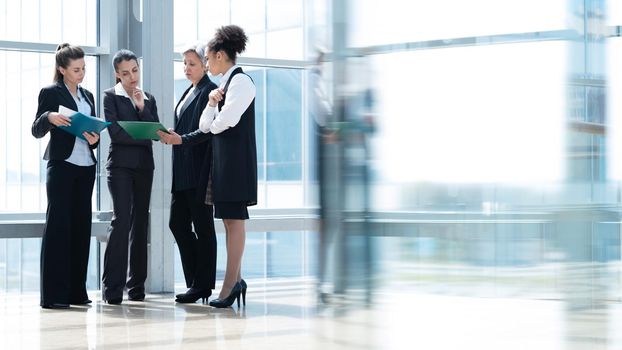 Multi ethnic group of business women in office lobby of modern building, female coworkers and communication concept