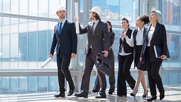 Team of construction industry workers engineer architect business people professionals walking together in modern lobby