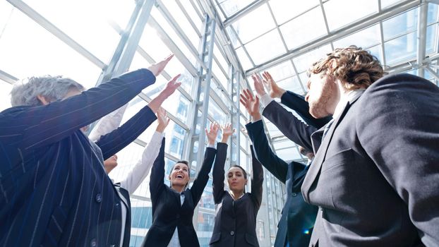Successful business people celebrating with a high-five in office building lobby