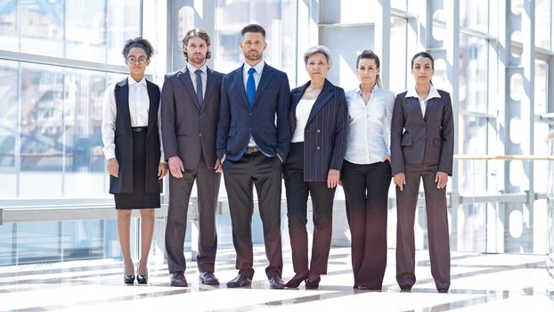 Multi ethnic group of confident business people in formal wear team indoors modern building full length portrait