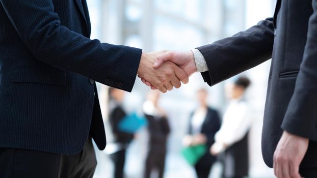 Close-up handshake of business people in front of colleagues team