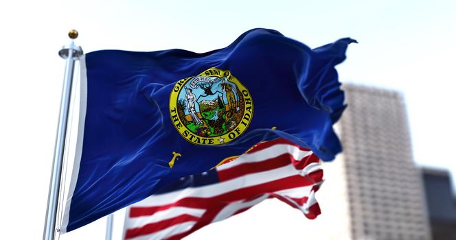 the flag of the US state of Idaho waving in the wind with the American stars and stripes flag blurred in the background. On July 3, 1890, Idaho became the 43rd state to join the Union