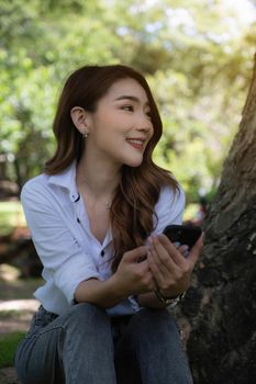 Portrait of Asian beautiful woman using smartphone at outdoor park