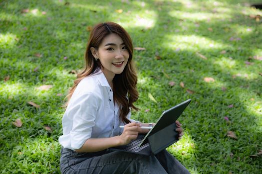 Student sitting in university park during break and research by tablet. Study, education, university, college, graduate concept