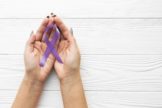 hands with violet ribbon wooden background. Resolution and high quality beautiful photo