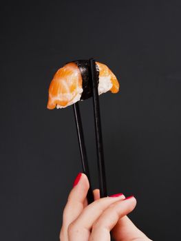 woman holding pair chopsticks with salmon sushi. Resolution and high quality beautiful photo