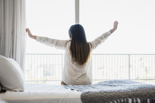 rear view woman sitting bed stretching her arms. Resolution and high quality beautiful photo