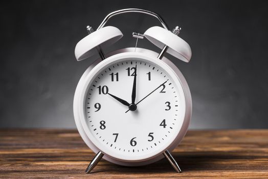 white alarm clock wooden textured table showing 10 oclock. Resolution and high quality beautiful photo