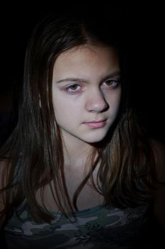 Facial portrait of cute teenage girl with long hair. Vertical shot, dark background