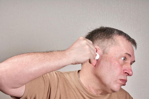 A man instills medicine into his ear with a small pipette from a pharmacy bottle. Self medication at home