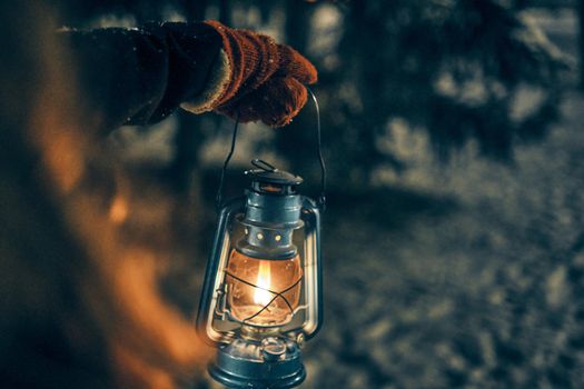 Young girl hand with lantern in winter forest fairy tale, book cover, christmas time