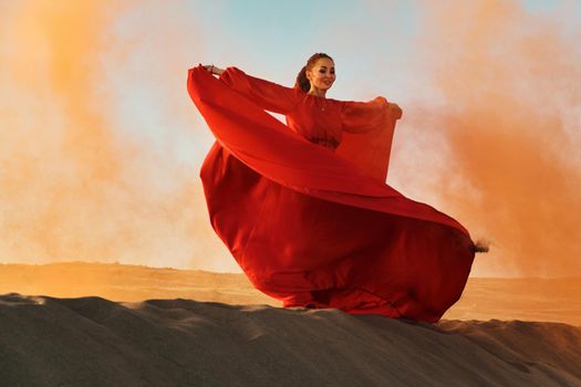 Woman in red dress dancing in the desert at blue sky