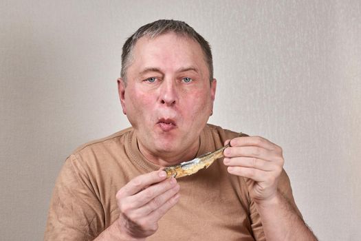 Man eating fried smelt fish holding fish with hands in front of face. Close up