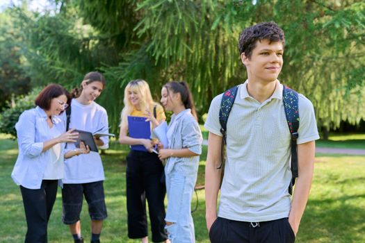 Portrait of male student in park campus, group of teenagers with teacher background. Adolescence, college, high school, education concept.