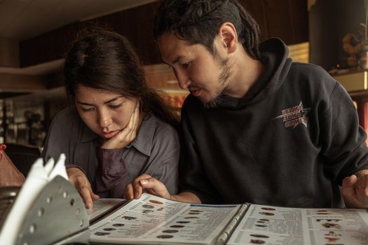 Young woman and man looking at a menu in a restaurant, Old Goa, India