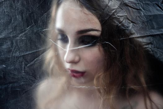 Young beauty sad woman trapped behind a plastic sheet as protection against COVID-19. Nicely fits for book cover