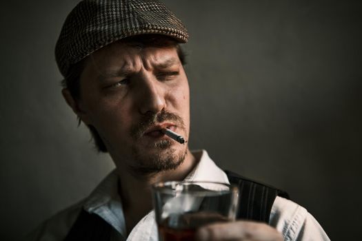 Young guy smoke a cigarette and drinks whiskey, blows smoke, dressed in a retro style, in a beret, cinematic shot, big closeup