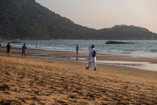 Man walking in waves on beach, Goa, India