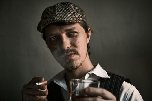 Young guy smoke a cigarette and drinks whiskey, blows smoke, dressed in a retro style, in a beret, cinematic shot, big closeup