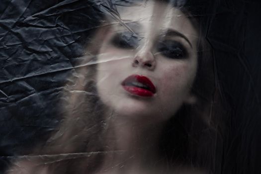 Young beauty sad woman trapped behind a plastic sheet as protection against COVID-19. Nicely fits for book cover