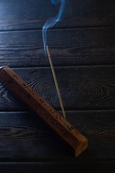 Focus on incense stick and smoke in a wooden stand. Symbol Japanese culture