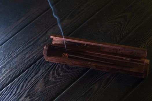 Focus on incense stick and smoke in a wooden stand. Symbol Japanese culture