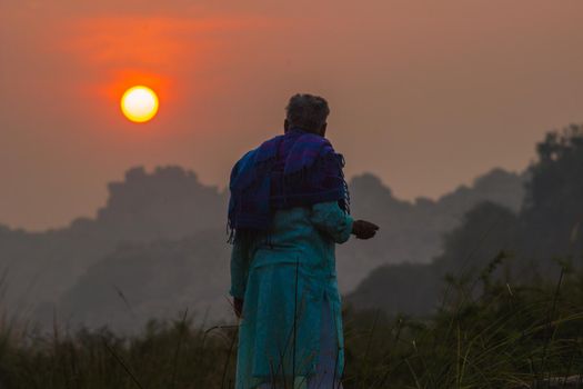 Rear view of a elder man looking at sunrise, India, Hampi