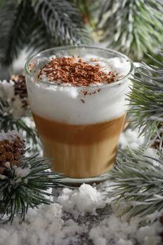 Christmas latte macchiato. A great hot coffee drink with chocolate shavings, among the snow-covered pine branches and snow.