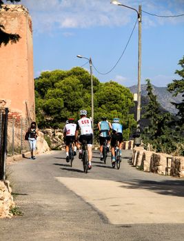 Alicante, Spain- September 18, 2021: Group of cyclists riding on a mountain road in Alicante on a sunny day of summer