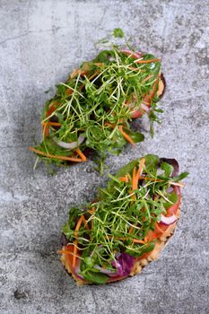 Sandwich toasted rustic bread with chickpea hummus, tomato slices, mix of lettuce and microgreens. Vegetarian breakfast.