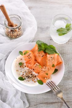 Gluten free vegetarian salad with carrot and yogurt seasoned with crushed nuts and spices, mint castings