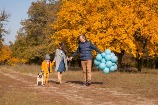 A young happy family with a small child and a dog wnjoy spend time together for a walk in the autumn park.