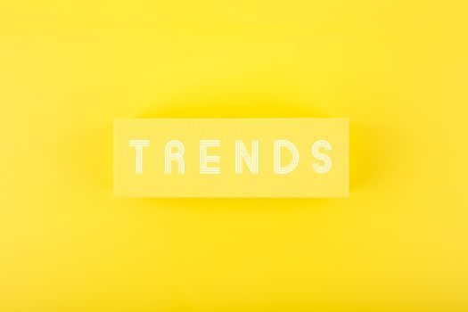 Minimal flat lay with word Trends written on rectangle on bright yellow background. Concept of newest, latest, hot and popular trends 