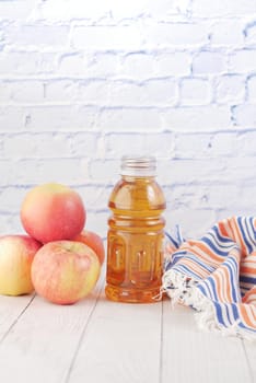 fresh apples and bottle of juice on table .