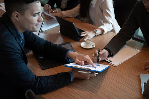 Group of business people pointing on financial report for analyze the company's sales plan in the office.