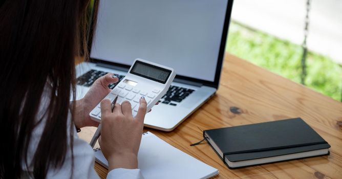 Business accounting concept, Business woman using calculator with computer laptop, budget and loan paper in office.