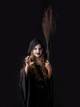 Girl in halloween evil angry witch costume grin snarl hold broom isolated on black background